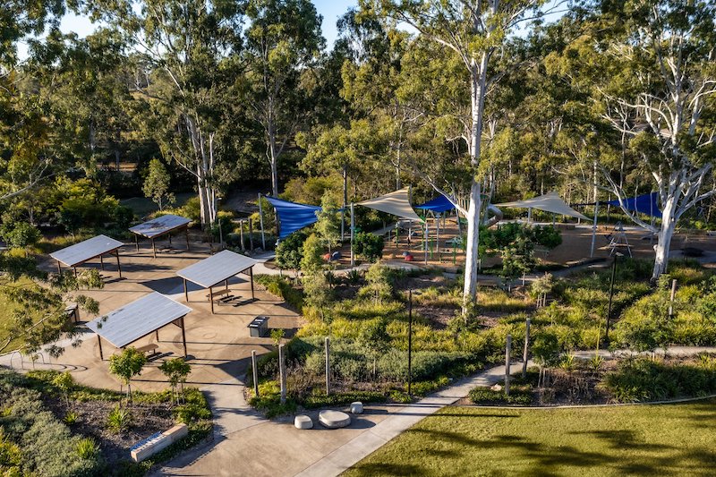 Parkland with shades, walking paths and playground nestled amongst gum trees and landscaping