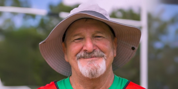Smiling man wearing a fluro top and baggy white hat