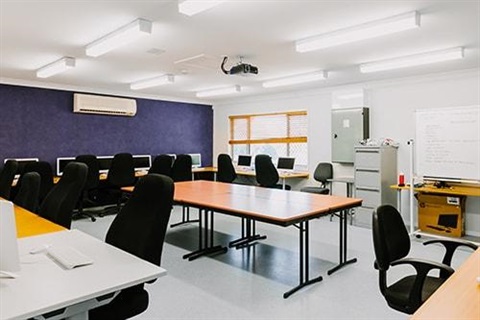 large room with a dark feature wall. Computers and desks lining three walls