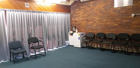 large room with brick walls and slanted roof. Red curtain on right had side and whiteboard on wall