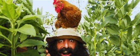 Costa with a chick on his head with a garden in the background