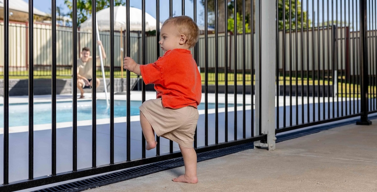 Child looking at pool through pool fence