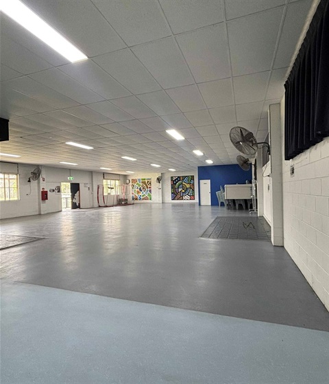 A spacious empty room featuring a ceiling fan and a decorative painting on the wall