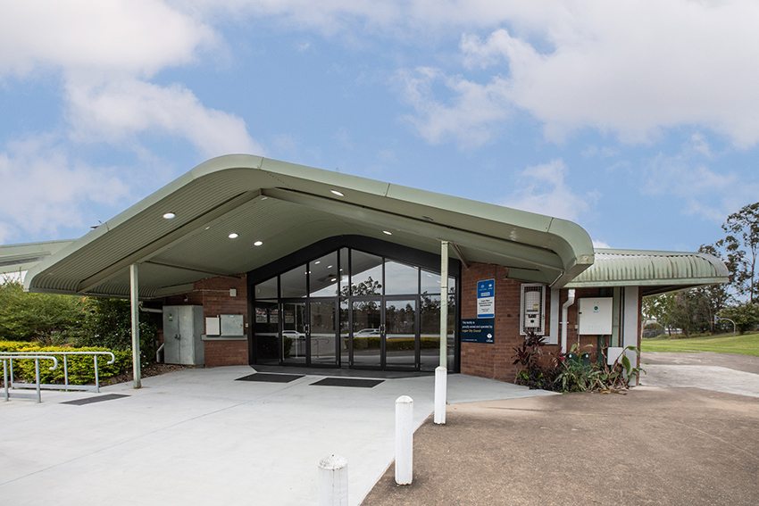 Single story brick building with light grey cement pathway leading up to the entrance