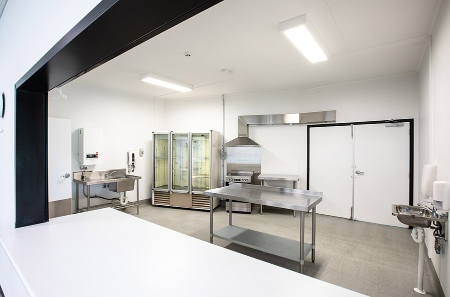 Kitchen area with double door fridge, oven, two sinks, preparation and serving areas.