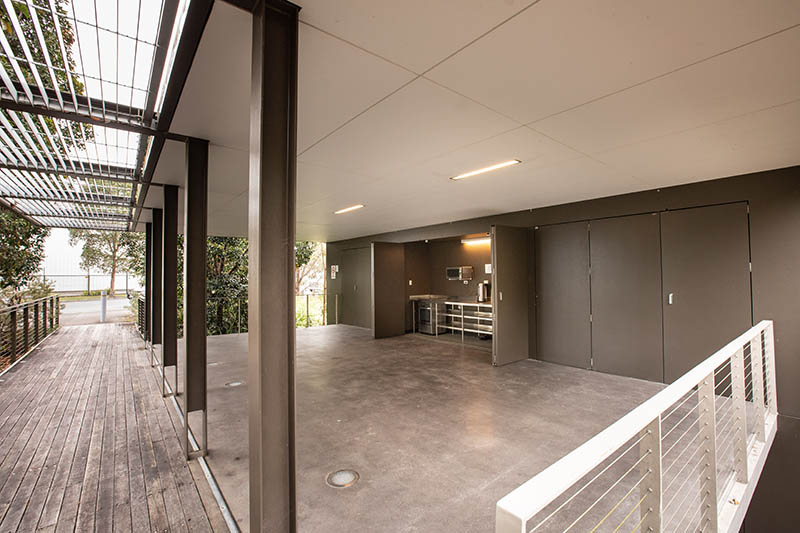 Under cover area with open cupboard showing kitchenette against the back wall.