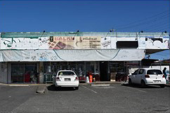 Frontage of shops at Logan Central before renovation, shop signage is busy and haphazard with visible ageing