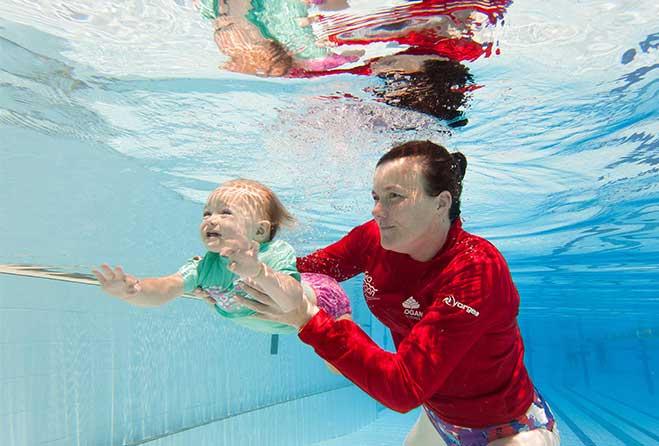 Women and baby swimming under water.