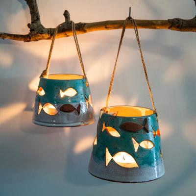 Two candles hanging from a branch with shing light coming from the candles