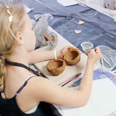 Young girl moulding a small clay bowl
