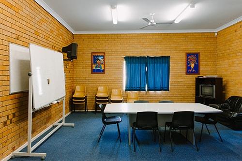 brick rom with blue carpet. small tabe and white boards