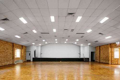 Large brick room with wooden look flooring and a large stage at the front of the room