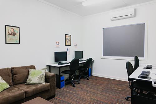 White room with computers and a brown couch