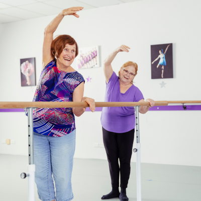 Two elderly women doing a plie