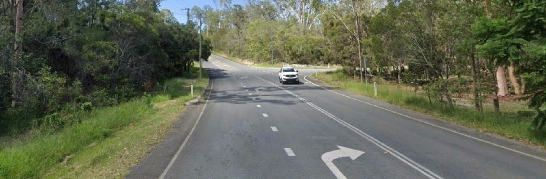 A car driving on a road with trees on both sides on Edelsten Road