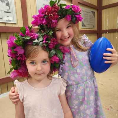 Two young girls smiling together with flower crowns