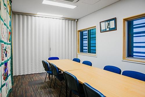 White carpeted room with long wooden table and blue chairs