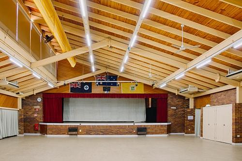 Brick room with exposed beams. stage at front of room with red curtains