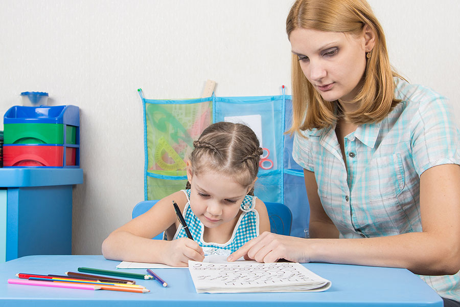 Mother helping child with writing