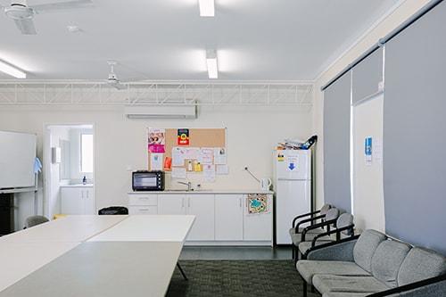 Large white room with a kitchenette, tables and chairs