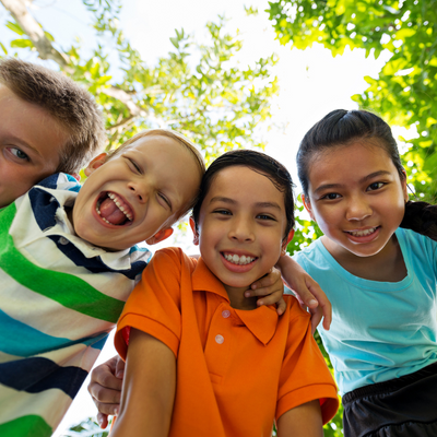 four kids smiling together in nature