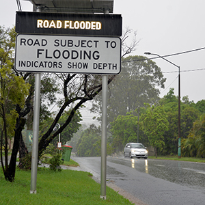 An image of a Road Flooded sign to illustrate that more than 100 roads across the City of Logan are impacted by local moderate flooding and storm damage.