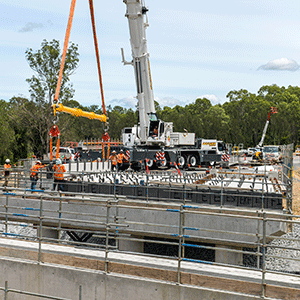 Crane lifts girders into place on bridge at construction site