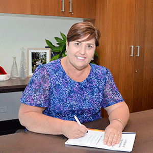 Woman signs certificate sitting at desk