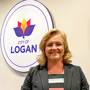 Woman stands in front of logo for Logan City Council
