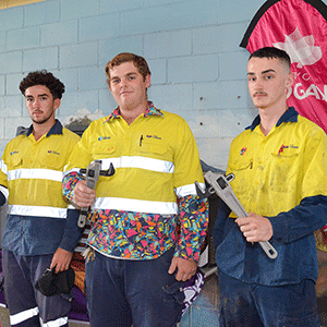 Three apprentices hold tools.