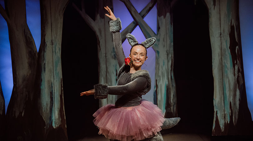 Woman dressed in mouse costume posed on a stage