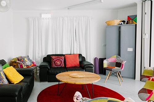 The hub meeting room with two relaxing black leather couches and a number of colourful cushions and chairs around the room.