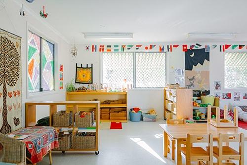 Colourful room with childrens toys and book cases, small childs table and decorative art on the wall.