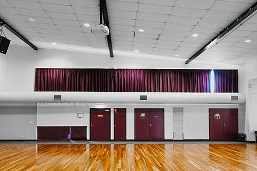 Main hall, white walls with burgundy doors and wooden floors.