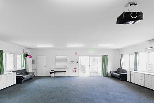 Carpeted room with white walls and green curtains. Two dark leather couches and storage along the walls