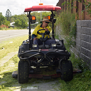 An image of Logan City Council's David Franz on a ride-on mower as he gives an overgrown footpath a trim