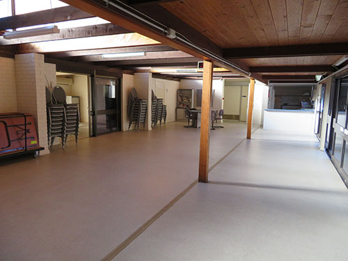 Open indoor area with chairs stacked in corner