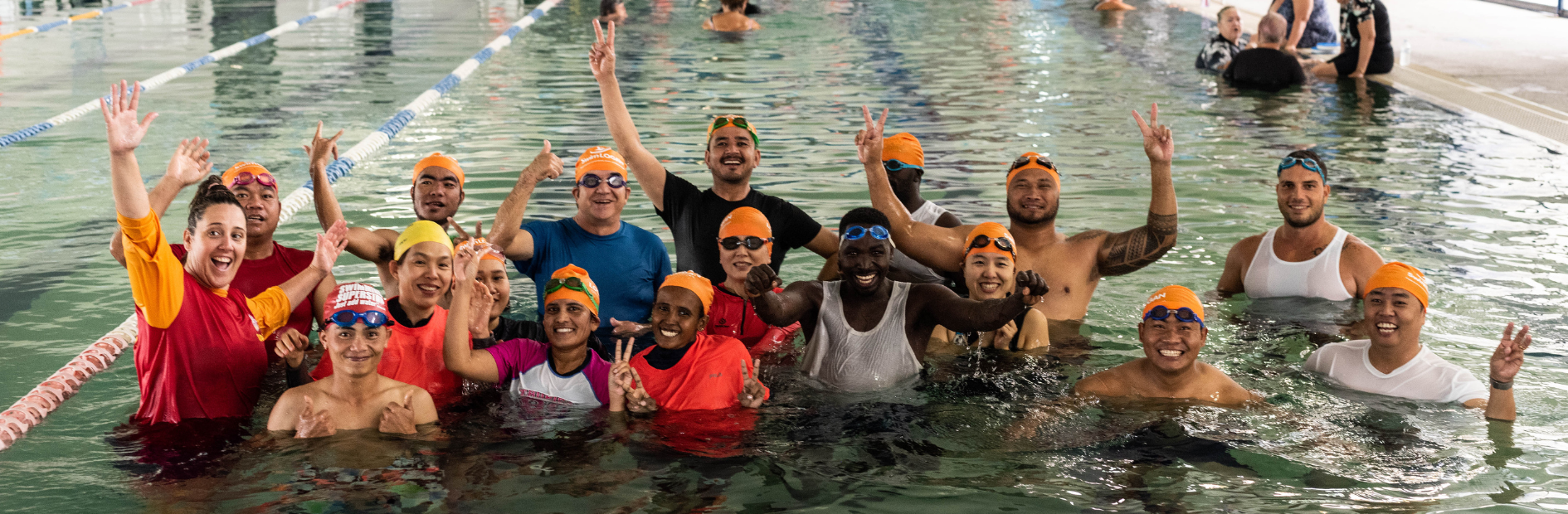 A large diverse group of people smiling and posing together while in the pool