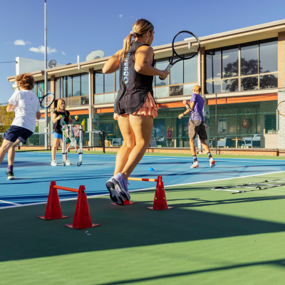 Girl dressed in tennis uniform jumps through obstacle course