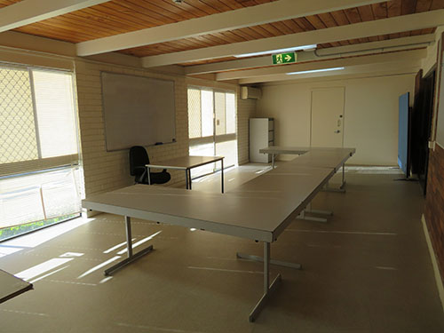 White tables set out in U shape in centre of a small room