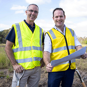 Two men look at plans at the site of a new park that will be constructed