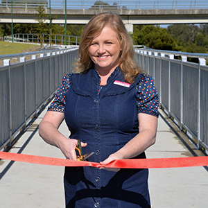 An image of City Lifestyle Chair and Division 4 Councillor Laurie Koranski cutting a red ribbon as she opens the new Logan Village River Link.