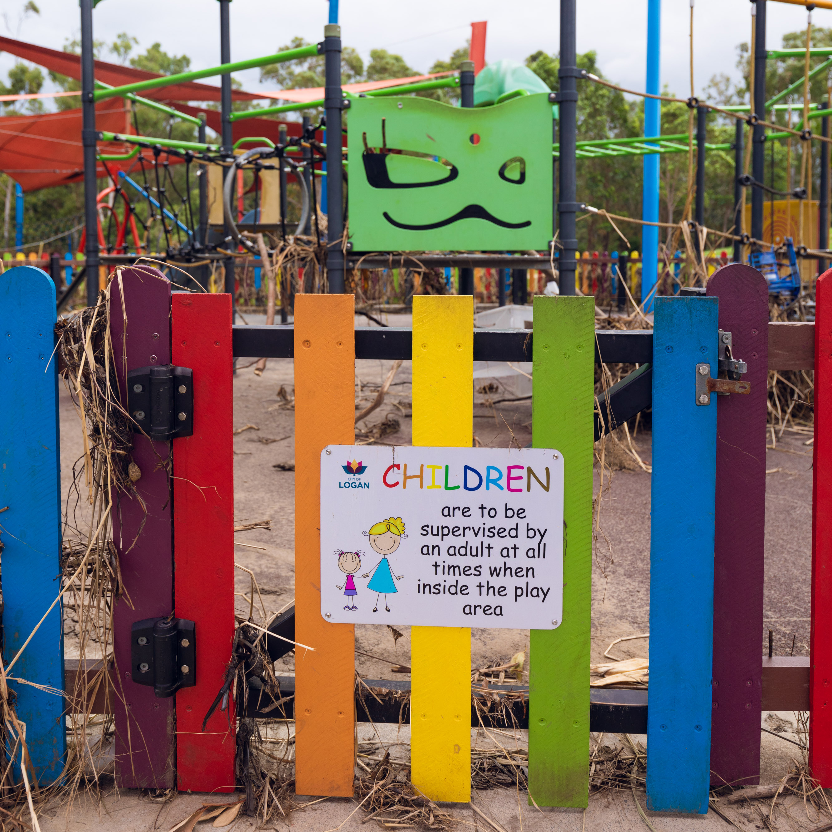 An image of a debris-covered playground fence at Logan River Parklands to show flood damage in City of Logan parks.