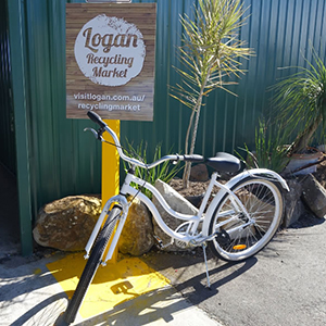 An image of a restored white bicycle outside the entrance to the Logan Recycling Market whihc reopens on Friday, June 12.