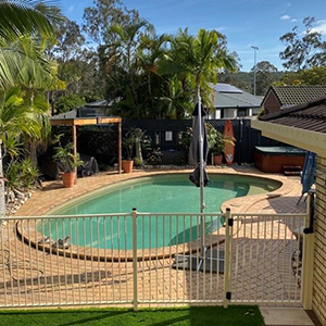 An image of a pool next to a house to illustrate that now is the time to check that your pool fence is safety compliant.