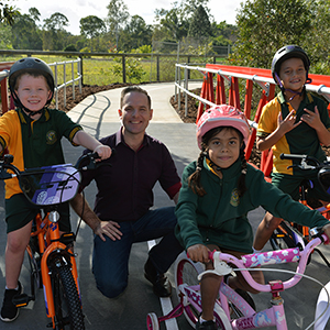 A photograph of 
Logan City Council Deputy Mayor Jon Raven with Oscar Ferguson, 7, Jade Green, 7, and Kodi Wills, 8, from Marsden State School, on the mini 'Logan Red Bridge' at the Demeio Park cycle safety circuit which opened in Marsden today.