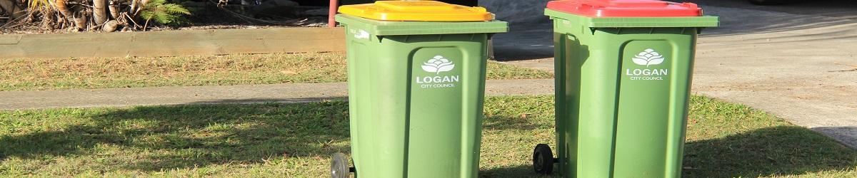 Wheelie bin with red lid and wheelie bin with yellow lid on sidewalk outside a house