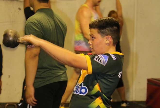 Young boy doing exercise with weights.