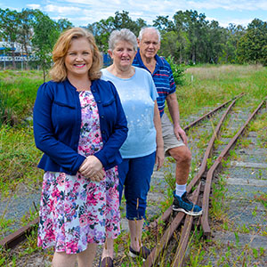 Three people stand on dis-used rail line