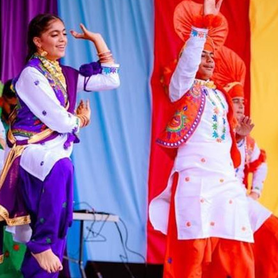 Dancers in brightly coloured clothing dance on stage decorated with bright decorations